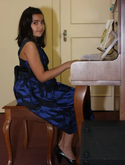 A student performing at the piano with sheet music
