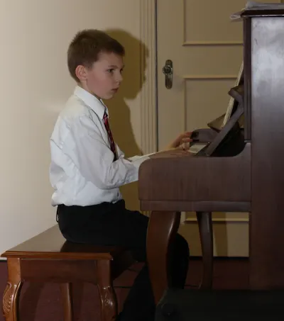 A young pianist looking up from the keyboard