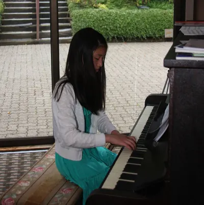 A student reading music while playing the piano
