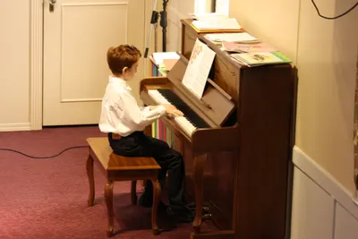 A young student playing piano at a studio recital