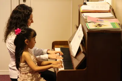A teacher and young student sharing the piano bench