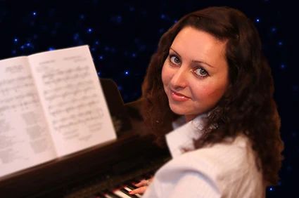 Olga Kolotygin seated at the piano with sheet music